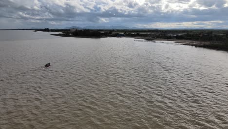 imágenes aéreas de drones de 4k de un barco de pesca de madera que navega de regreso a un pueblo en tailandia
