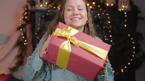 brunette, blue-eyed girl delightfully receives red gift