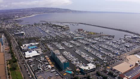 High-and-wide-aerial-panning-shot-of-the-King-Harbor-Marina-looking-towards-the-Palos-Verdes-peninsula-in-Redondo-Beach,-California