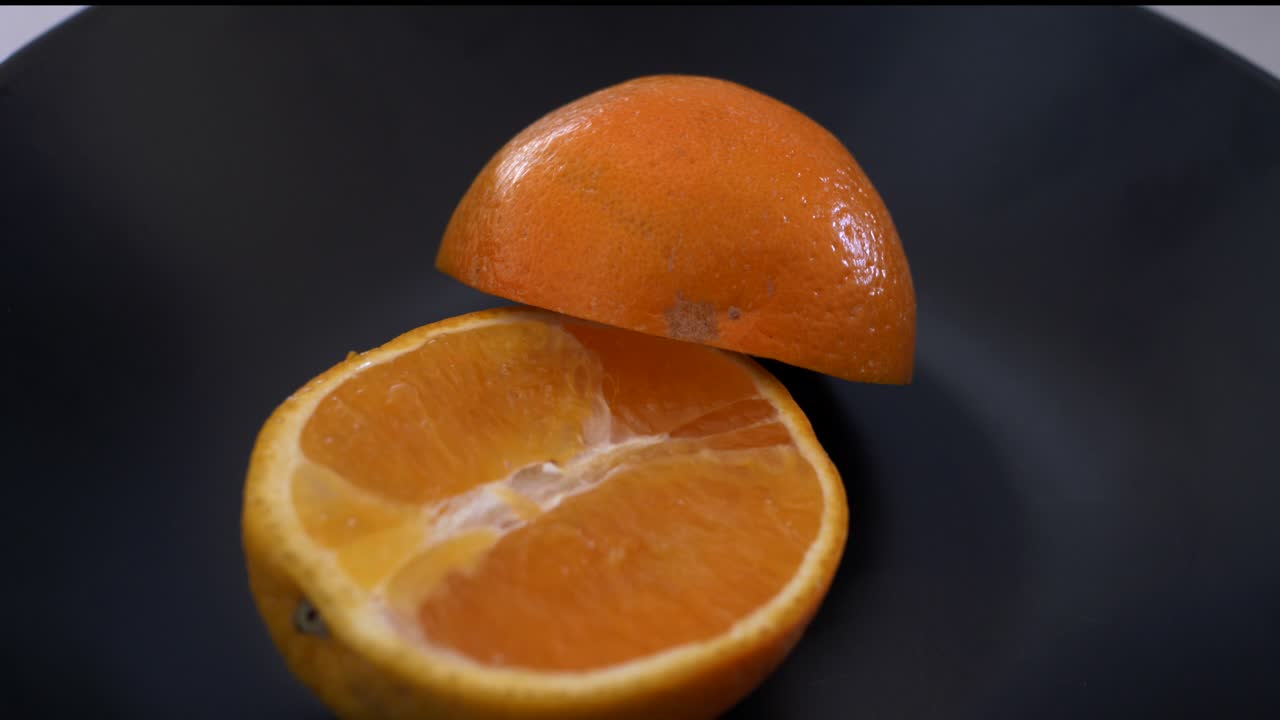 panorámica a cámara lenta alrededor cortada por la mitad de naranja en un plato negro