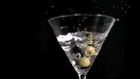 oliven in super langsamer bewegung, die in einen martini fallen