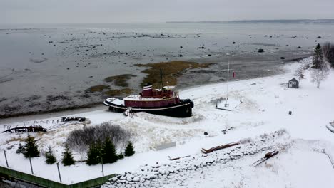 drone flying around a docked ship on the edge of the saint-lawrence river in winter