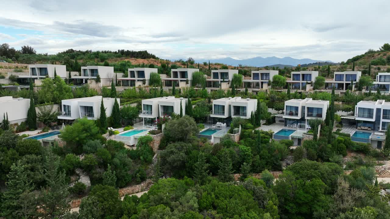 Aerial: vacation beach house with pools during the day in Sarande, Albania, establishing drone shot