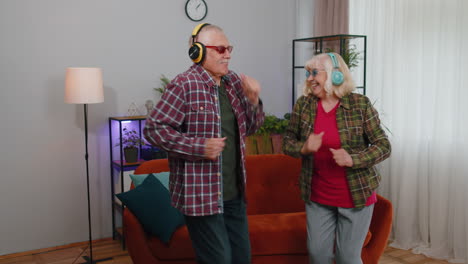 happy senior grandparents man woman listening music dancing disco fooling around having fun at home