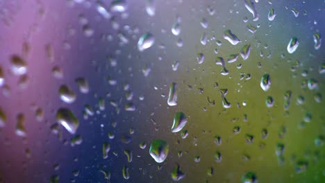waterdruppels die op vensterglas vallen. regendruppels die afgetrokken vallen. druppels die naar beneden lopen. kleurige achtergrond.