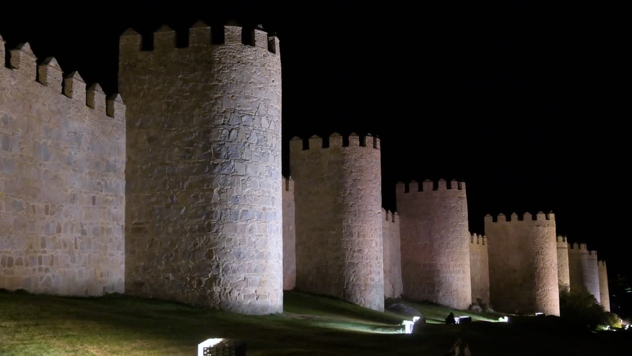 A twilight view of Avila’s old town, featuring the brightly lit, UNESCO-protected medieval walls in Spain.