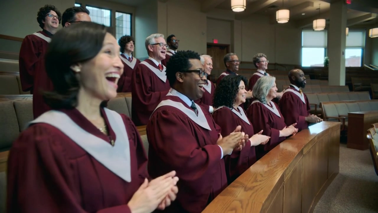 Song starting, choir singing and clapping near wooden rail, maroon-robed white-collared at church