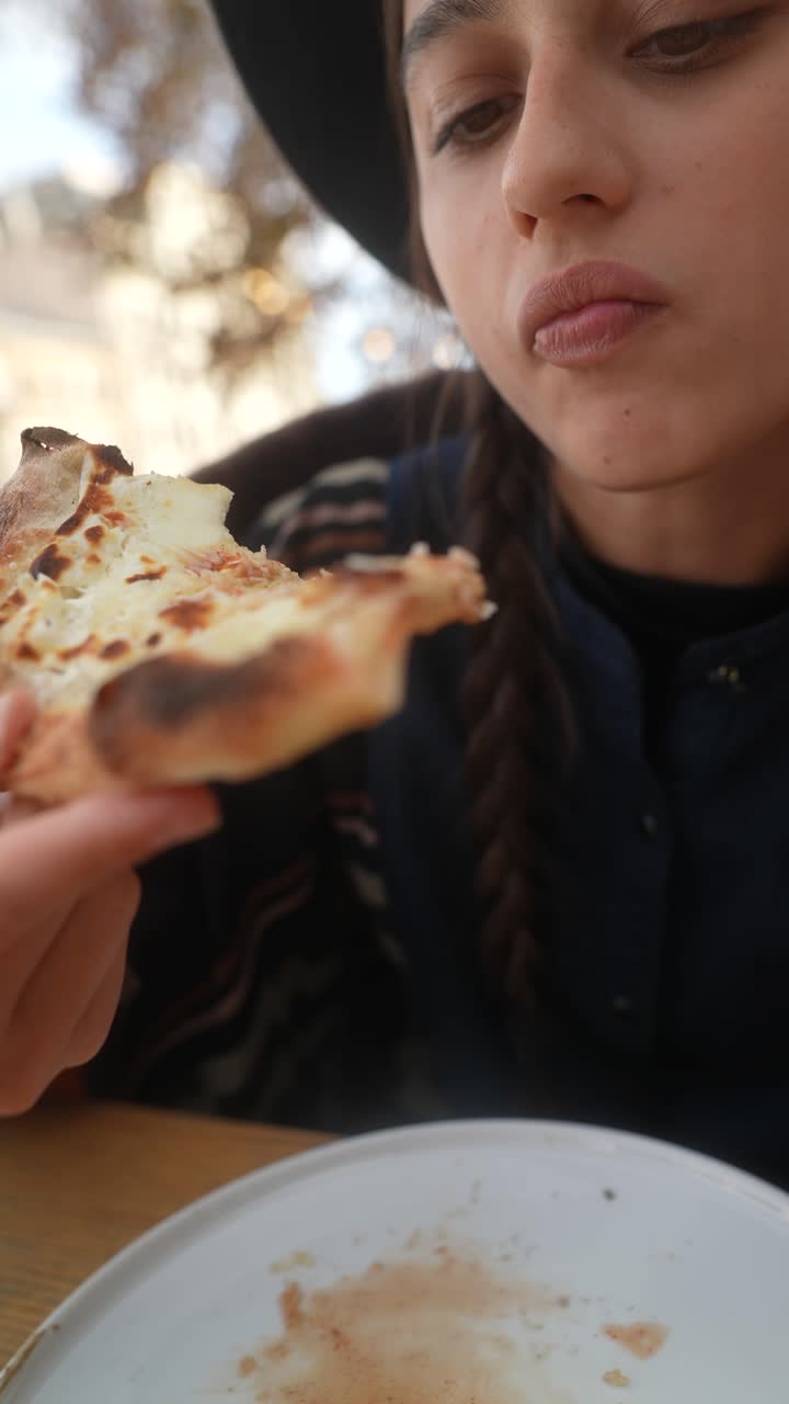una chica comiendo una rebanada de pizza.