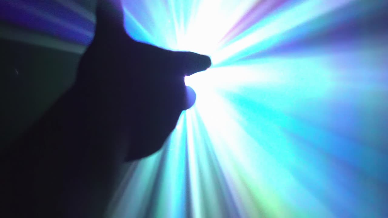 la mano se extiende hacia una fuente de luz pulsante de colores