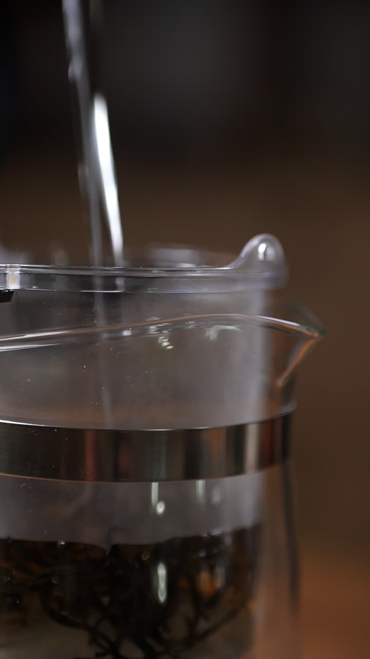 Pouring hot water into a glass tea pot