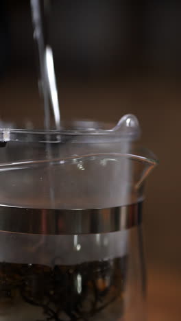 pouring hot water into a glass tea pot