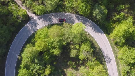 U-Turn-Straße-Von-Oben,-Während-Ein-Rotes-Auto-Die-Straße-Entlang-Fährt