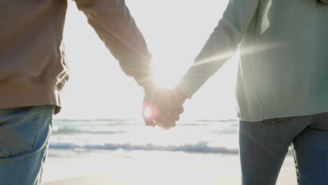 Sun,-holding-hands-and-couple-walking-on-beach