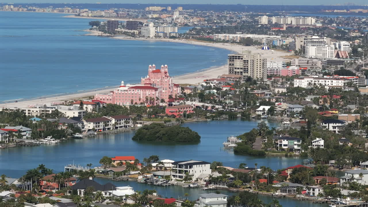 Sweeping aerial view of Saint Pete Beach looking north revealing waterfront homes with docks, The Don CeSar, and beachfront coastline vista with hotels and condos along Florida's scenic Gulf Coast