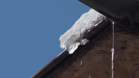 ice icicles hang from the roof against the blue sky