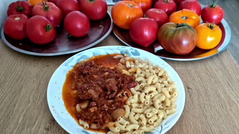 comida de pasta de macarrones en un plato junto a tomates orgánicos recién cosechados