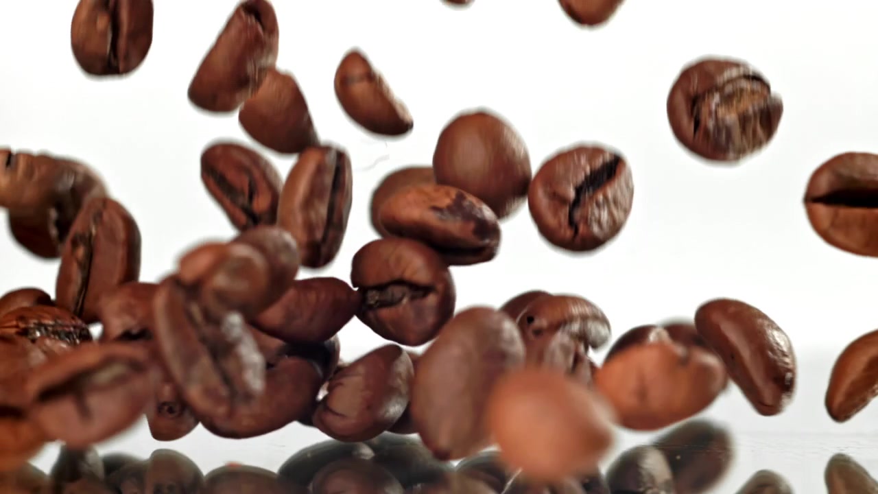 Chicchi di caffè tostati che cadono e rimbalzano al rallentatore.