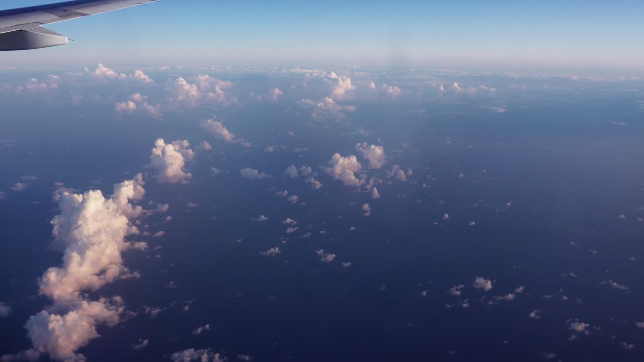 Udsigt fra vinduet af en flyvinge, der flyver over de små hvide skyer og det store blå hav på rejse til Aserbajdsjan