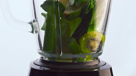 green fruits vegetables falling blender cup in super slow motion close up.