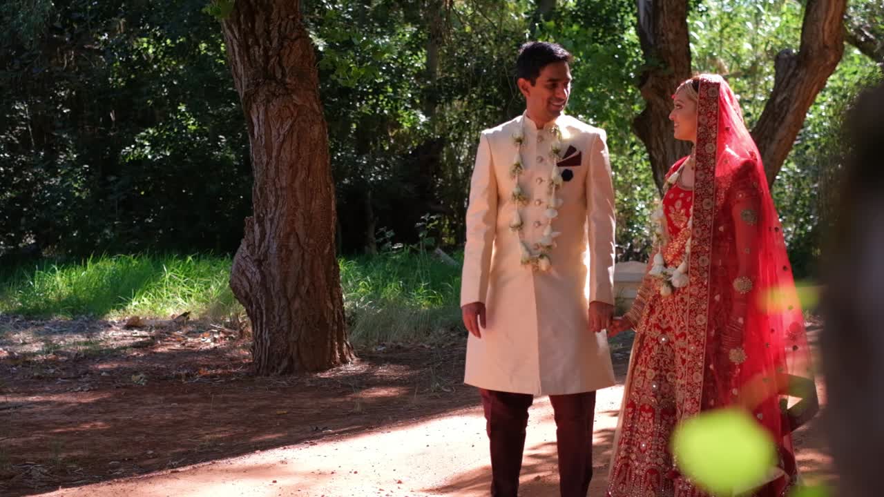 Traditionelt indisk par iført overdådige dragter under bryllup med naturbaggrund.