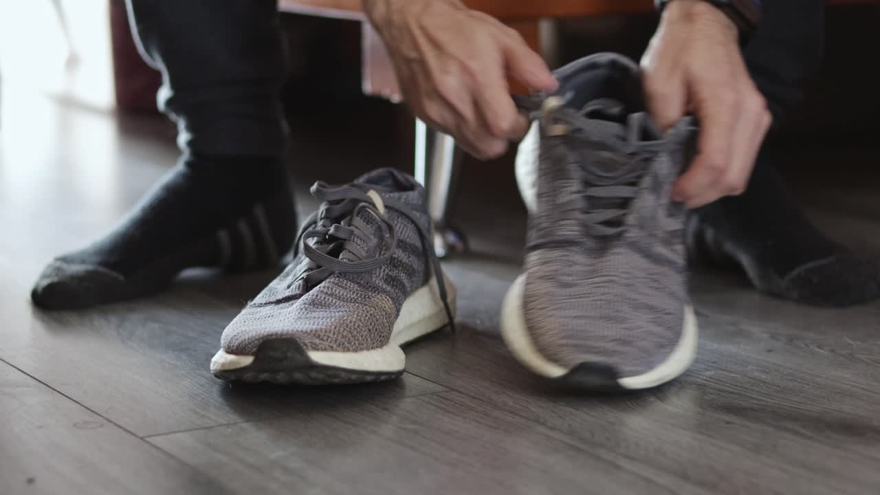 Primo piano di un uomo che si allaccia i lacci delle scarpe prima di andare a correre