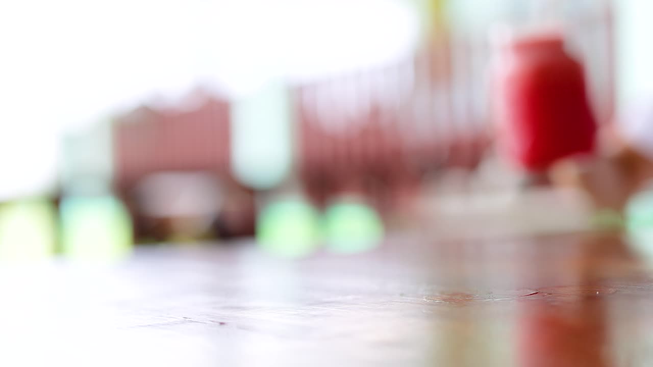 Hands serve vibrant watermelon juice in glass jars on a wooden table. Bright, natural lighting enhances the refreshing atmosphere