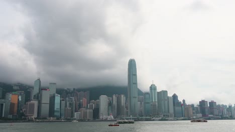 ferries and boats sail across victoria harbour on a cloudy day, with the iconic hong kong island financial district skyline as backdrop in hong kong, china.