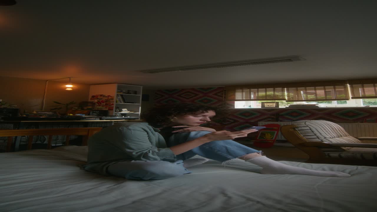 전화를 사용하여 침대에 앉아있는 젊은 여성