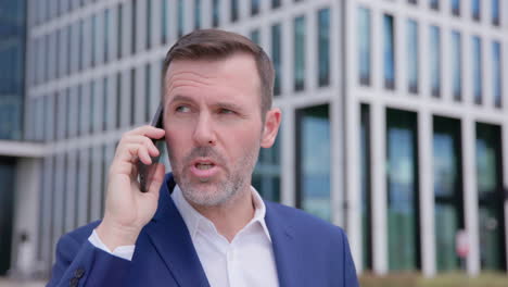 close-up of business man in suit walking and talking on phone outdoors