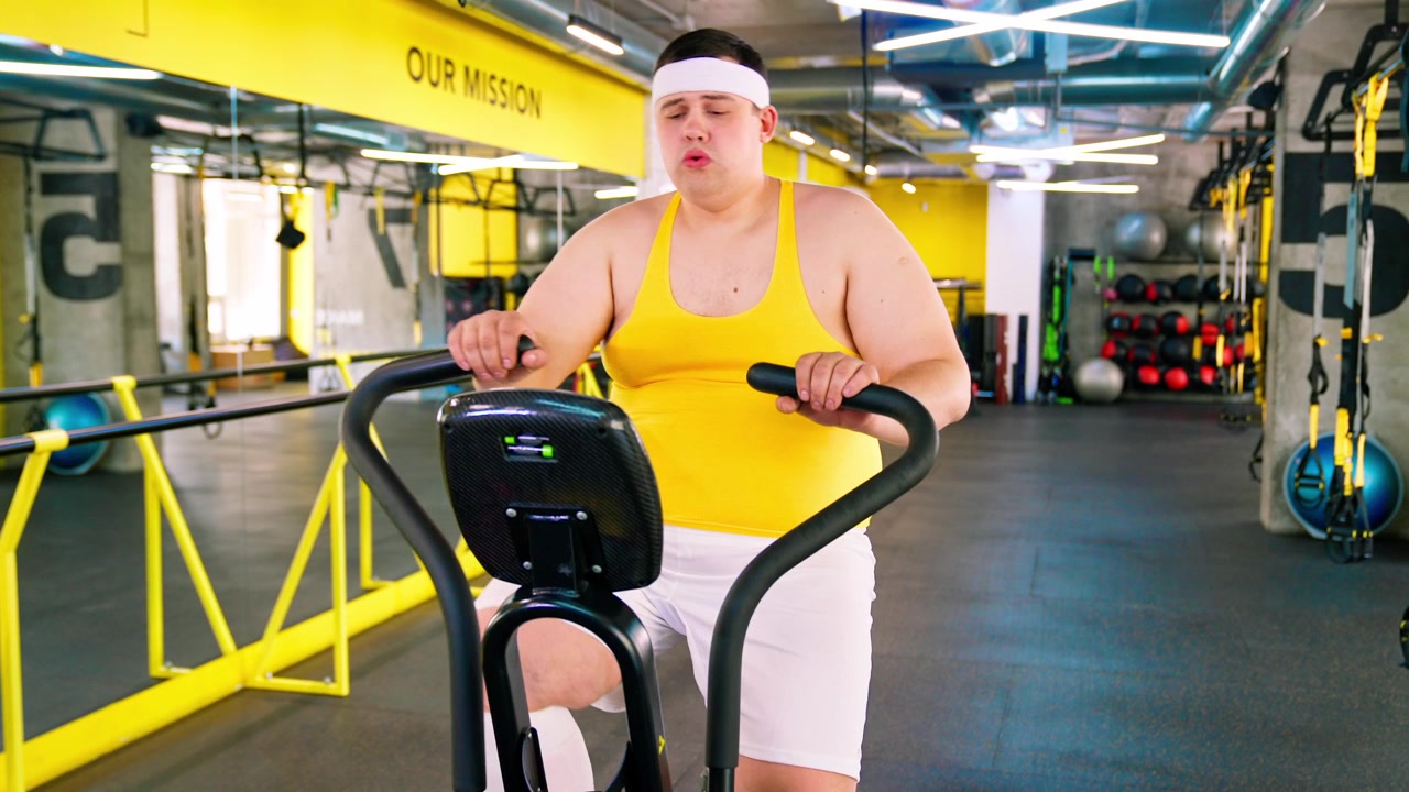 Uomo in sovrappeso che fatica ad allenarsi su un'ellittica in palestra