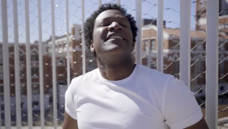 Closeup-shot-of-smiling-African-American-man-standing-near-fence.