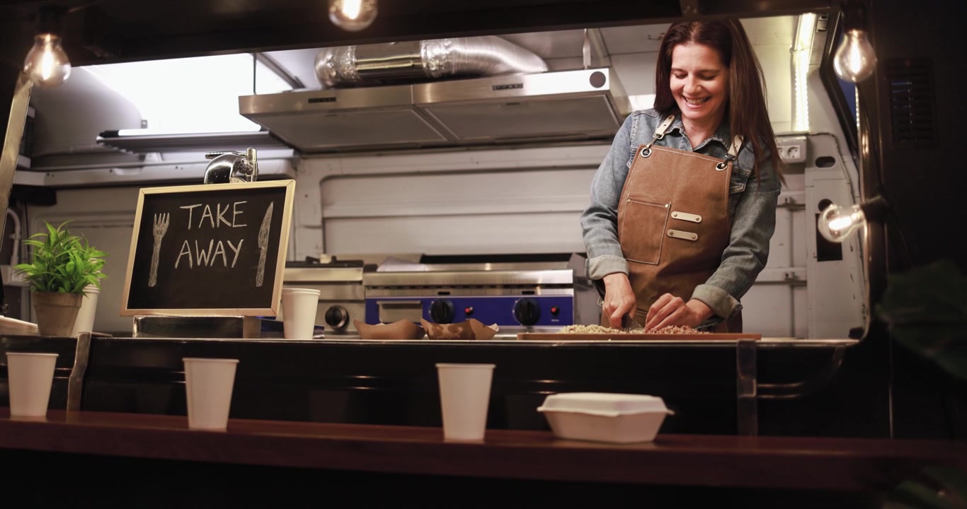 Donna sorridente che prepara cibo in un food truck da asporto