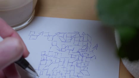 video en primer plano de una mano humana dibujando bocetos en papel en una mesa de trabajo