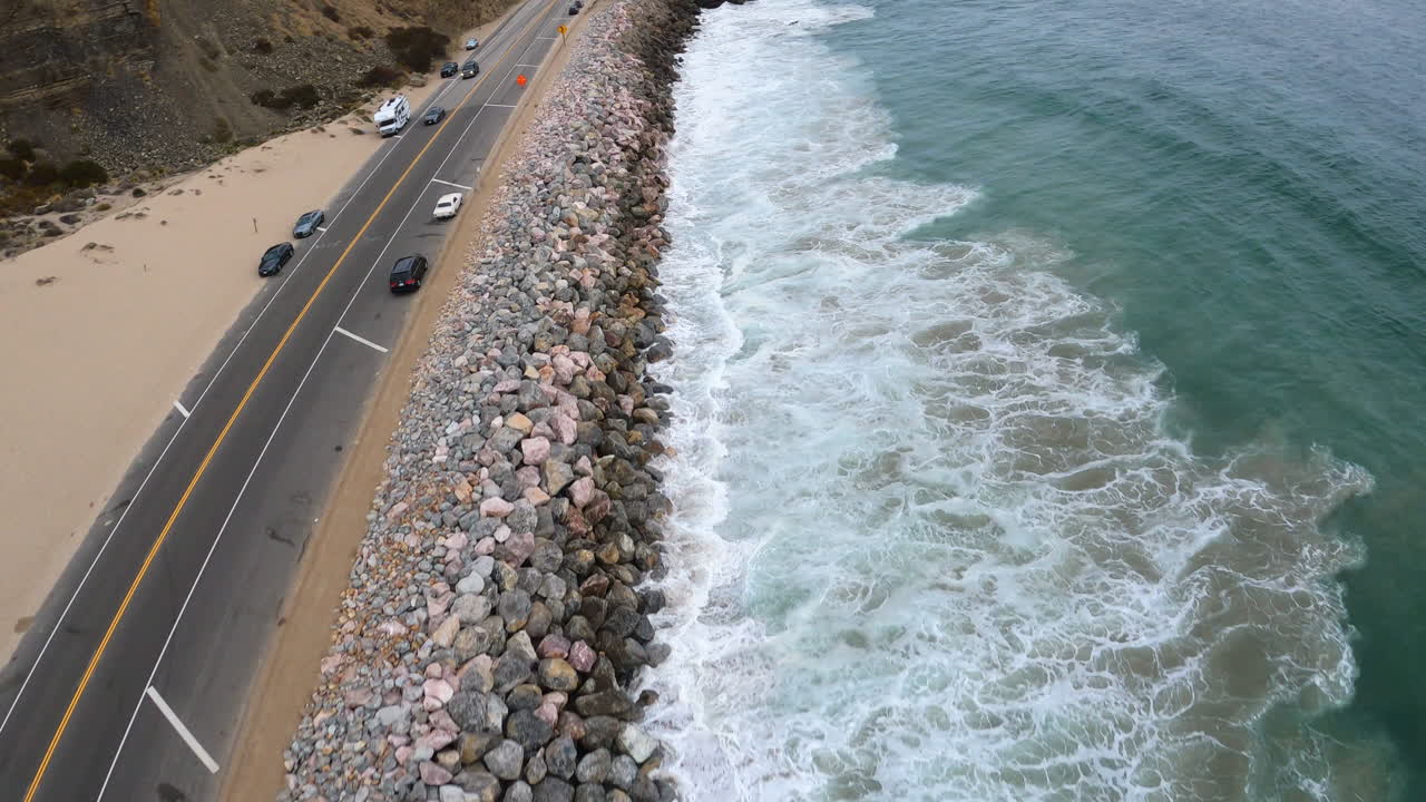 olas del océano pacífico rompiendo en la costa de california, drones aéreos disparados sobre el tráfico en movimiento