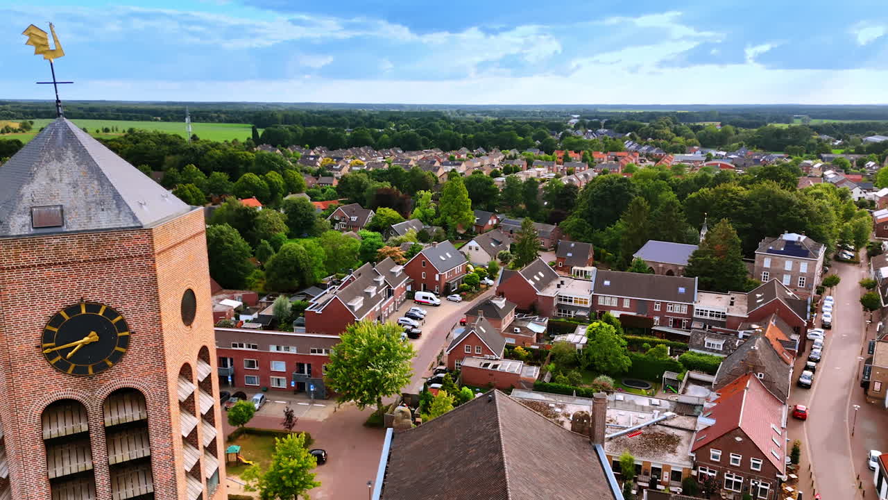 Approaching the tower of Saint Lawrence Church in Vierlingsbeek, Netherlands. Aerial perspective on the residential area with lush greenery