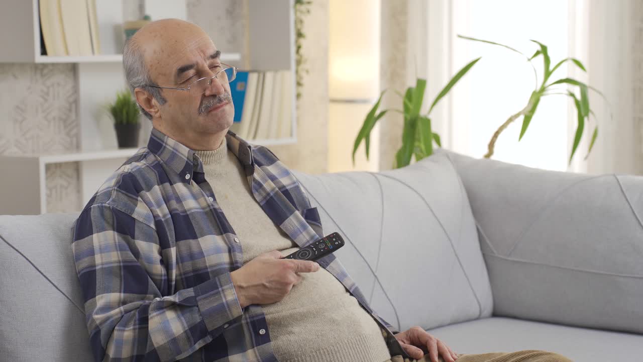 L'anziano si addormenta sul divano mentre guarda la TV.