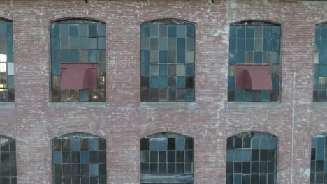 Panorámica-Por-Las-Viejas-Ventanas-De-Una-Fábrica-De-Algodón-Abandonada-Durante-El-Amanecer-Mientras-La-Luz-Del-Sol-Llena-La-Habitación-Vacía-En-Mckinney,-Texas