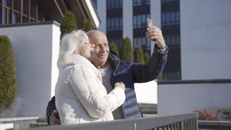 senior couple making a selfie with smartphone in the park on a winter day