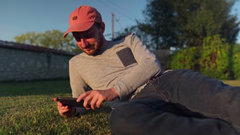 young man taking time out to relax outside and keeping entertained on smartphone