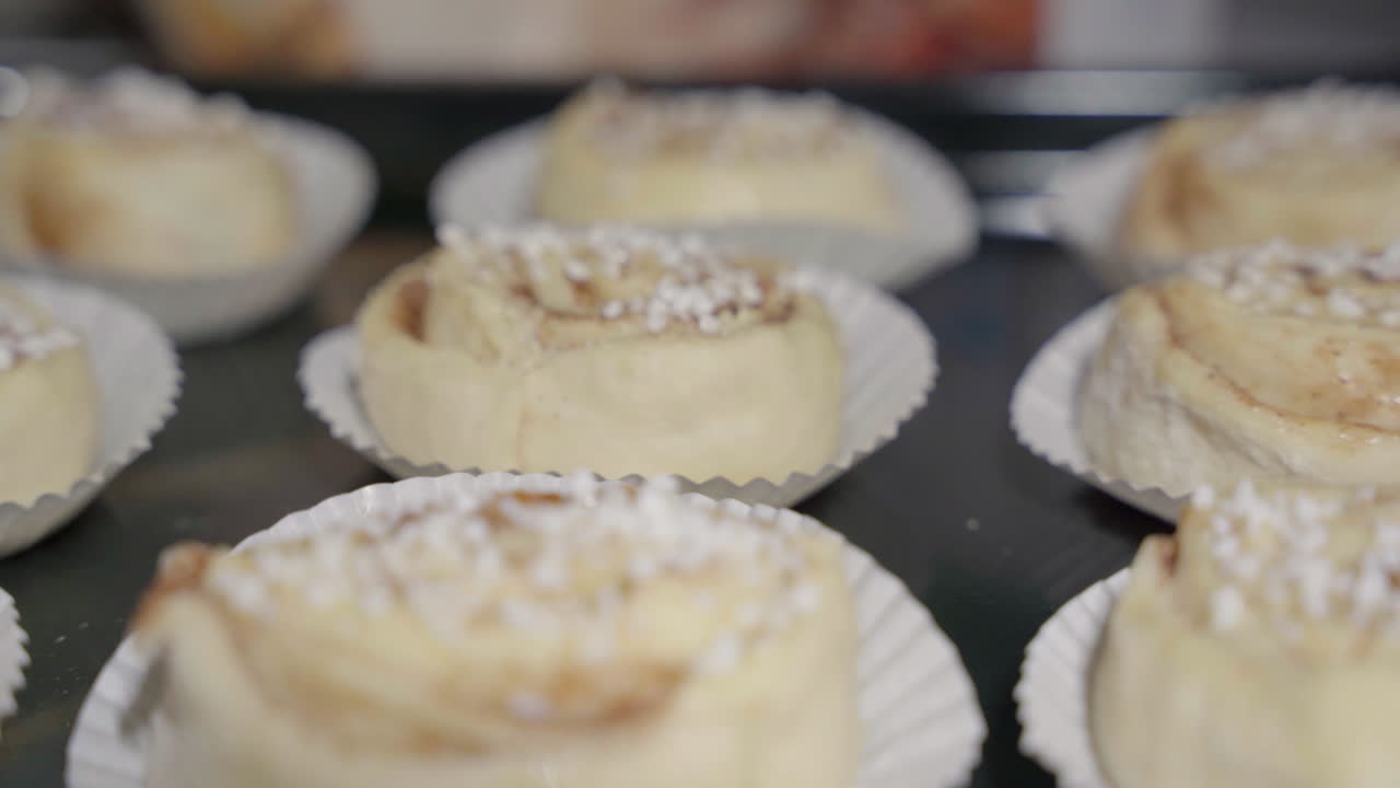 toma de diapositivas medianas de bollos de canela crudos sin hornear en una bandeja