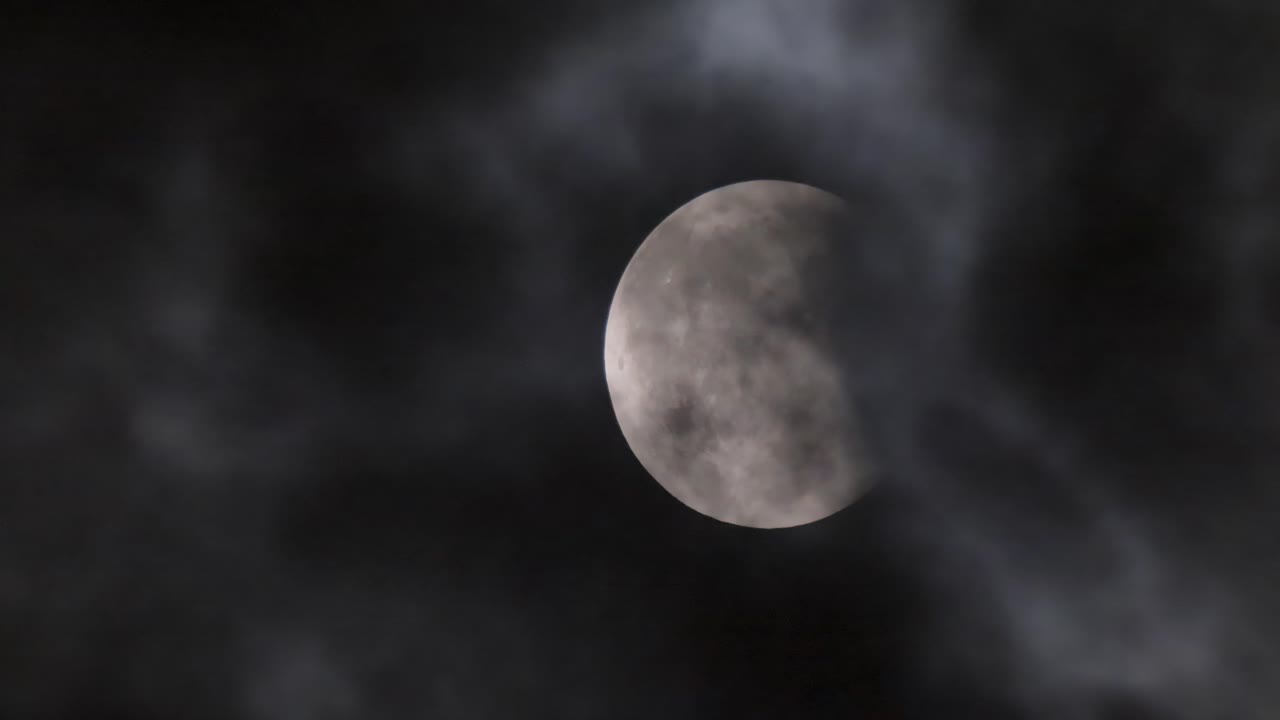 Lunar eclipse. The moon on the background of a dark sky with clouds
