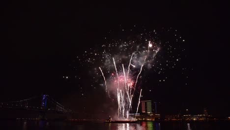 un espectáculo de fuegos artificiales se lleva a cabo sobre el agua por un puente en américa