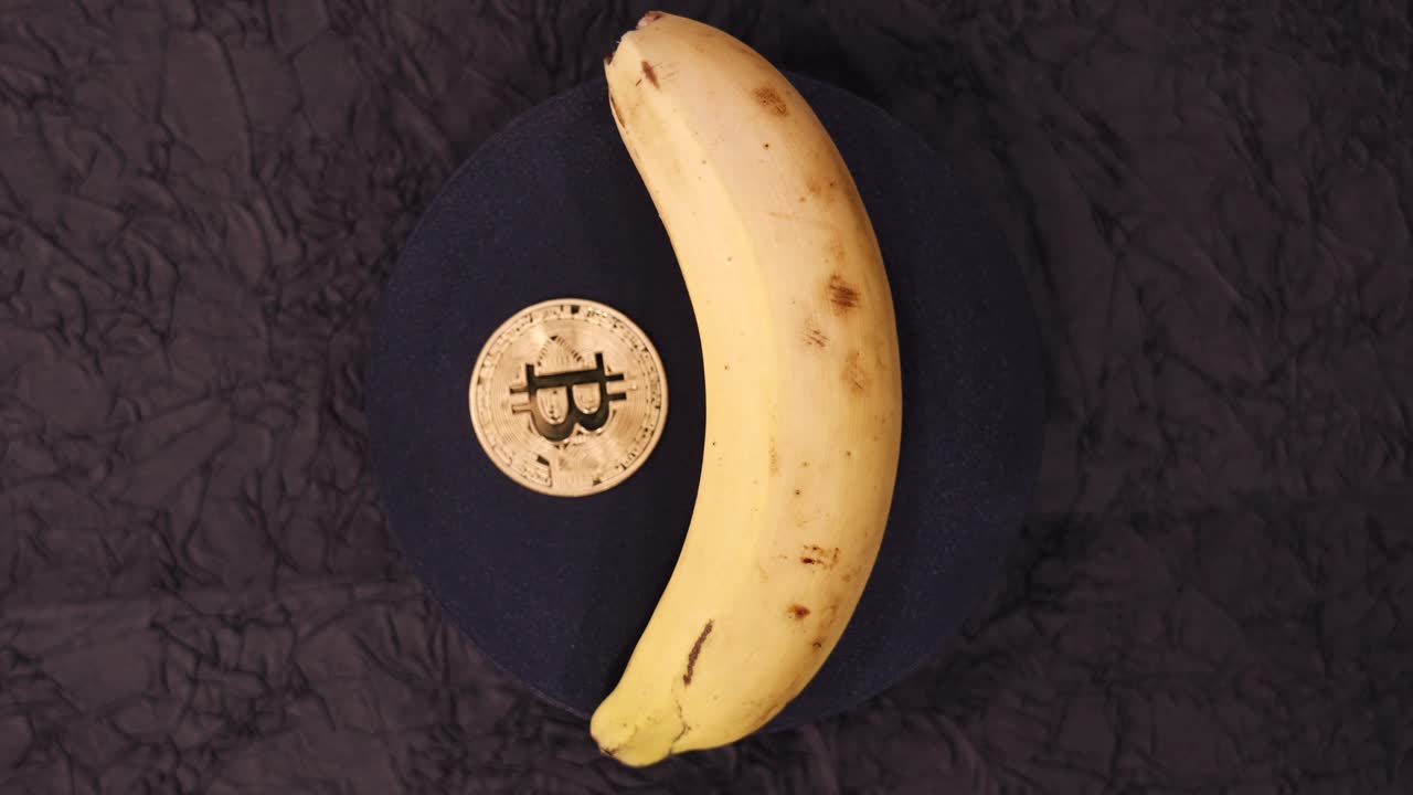 Spinning Banana And Bitcoin Coin On Round Surface. - high angle shot