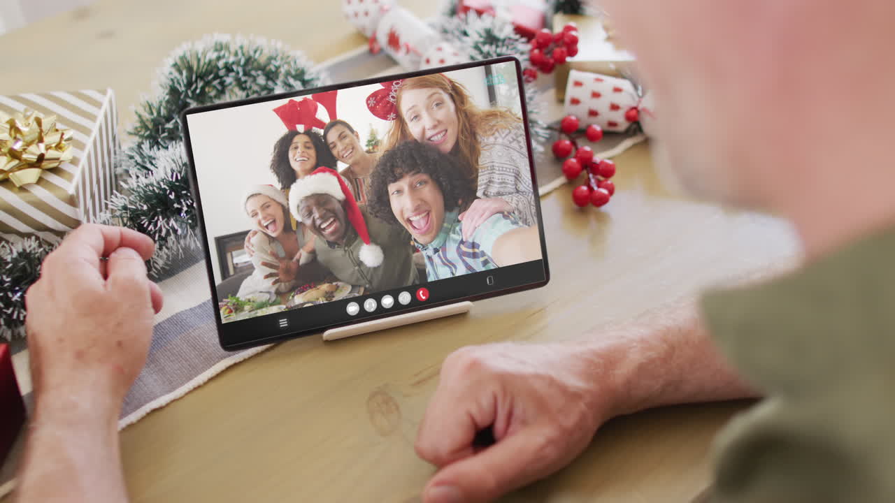 un hombre caucásico mayor tiene una videoconferencia de navidad con personas diversas.