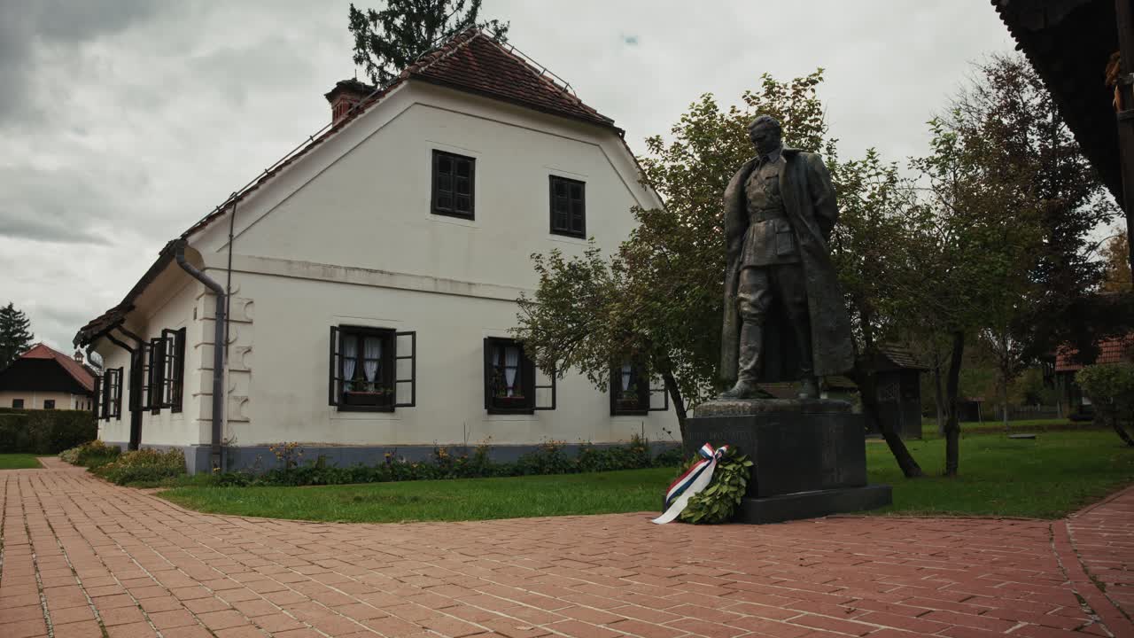 Statue of Josip Broz Tito beside a traditional house in Kumrovec, Croatia, evoking history
