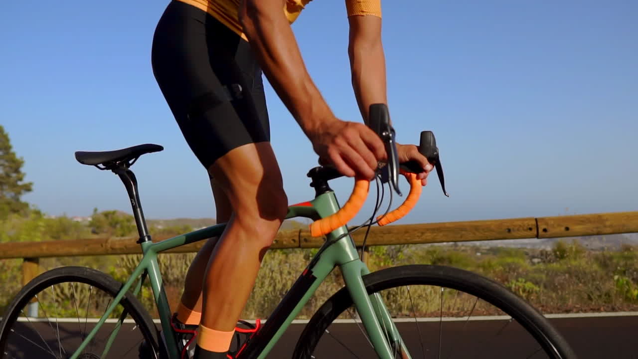 capturado en la cámara es un video de seguimiento de un ciclista masculino que sube por una carretera de montaña. se dedica al entrenamiento en bicicleta a lo largo de una carretera montañosa en un día soleado