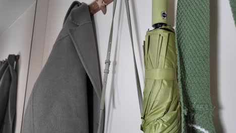 coat, umbrella, and scarf hanging on a wall hook