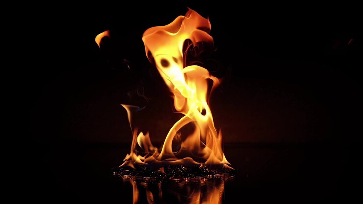 Fiamme al rallentatore che bruciano su una superficie riflettente nell'oscurità