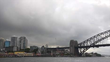 a train passes over the sydney harbour bridge on an overcast rainy day in sydney, australia