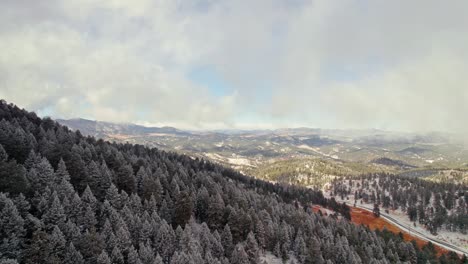 Vista-Aérea-De-Drones-Volando-Sobre-El-Paisaje-De-Laderas-De-Pinos-Nevados-De-Invierno-Y-Cadenas-Montañosas-Cerca-De-Kittredge-Evergreen-Colorado